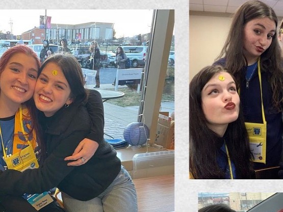 Two students at the conference, one with a sticker stuck on her forehead